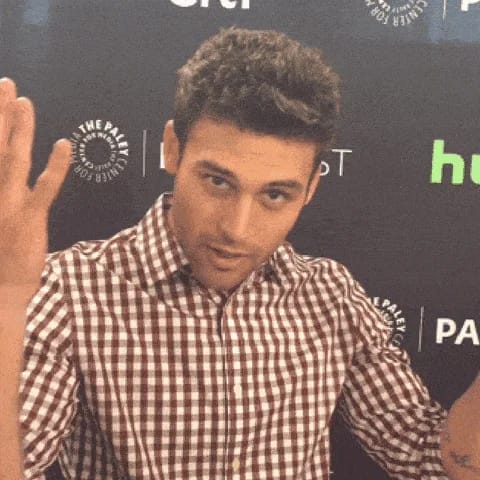 Homme en chemise à carreaux devant fond "Paley Center for Media" présentant un geste ouvertement expressif.